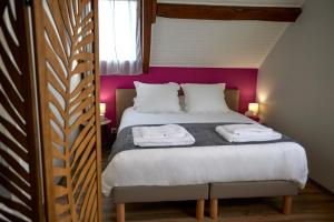a bedroom with a bed with a pink wall at L'Appart de La Grande Boutique du Vin Beaune in Beaune