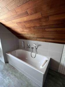a white bath tub in a bathroom with a wooden ceiling at Gasthaus Maarfeld Gerolstein in Gerolstein
