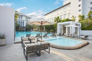芭達雅南區的住宿－Health Land Resort & Spa，一座带椅子和遮阳伞的游泳池位于一座建筑旁边
