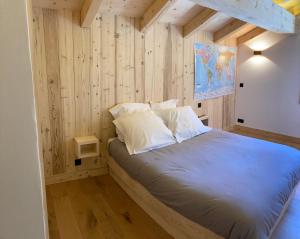 um quarto com paredes de madeira e uma cama com almofadas brancas em Superbe Chalet à Megève 7 pers Près des Pistes em Demi-Quartier