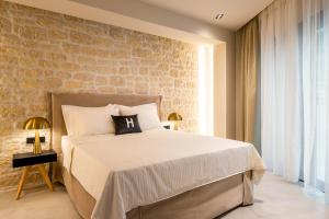 a bedroom with a large bed and a brick wall at Hara Suites in Parga