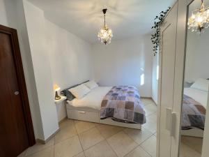 een kleine slaapkamer met een bed en een kroonluchter bij Gavirate Cozy Apartment BBQ/Garden in Gavirate