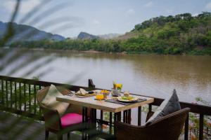 - une table sur un balcon avec vue sur la rivière dans l'établissement Ock Pop Tok Mekong Villa, à Luang Prabang