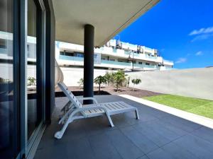 uma cadeira branca sentada numa varanda com um edifício em Apartment 2 bedrooms and terrace em La Tejita