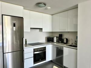 cocina con armarios blancos y nevera de acero inoxidable en Apartment 2 bedrooms and terrace, en La Tejita
