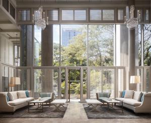 a lobby with large windows and couches and tables at Oriental Residence Bangkok in Bangkok