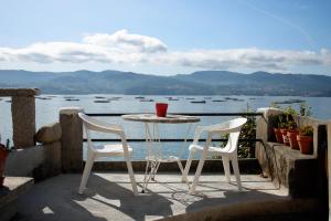 een tafel en stoelen op een balkon met uitzicht op het water bij Casa sobre o mar A Ceboleira in Raxo