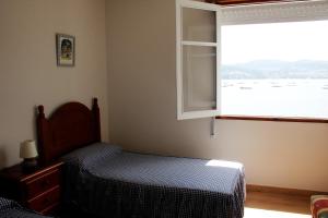 Habitación pequeña con cama y ventana en Casa sobre o mar A Ceboleira, en Raxó