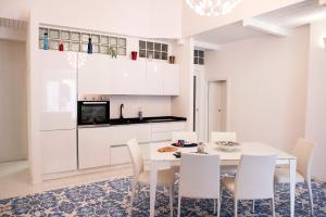 a white kitchen with a table and white chairs at River Song - Vietri sul Mare in Vietri