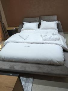 a large bed with white sheets and pillows at Ghazalle Oasis Hotel 1 in El Biar