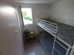 Cette petite chambre comprend des lits superposés et une fenêtre. dans l'établissement Appartement refait à neuf à 500m de la plage, à Torreilles