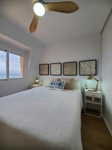 1 dormitorio con cama blanca y ventilador de techo en Jardin del Mar, en La Manga del Mar Menor