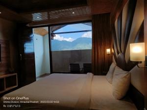 um quarto com uma cama grande e uma janela grande em The Jungle Mountain Retreat em Mundaghat 