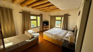 a bedroom with two beds and a tv in it at mandarava homestay in Leh
