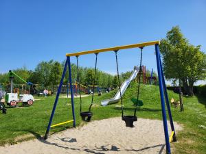 een speeltuin met schommels en glijbanen in een park bij Het Huisje comfortabel, luxe & sfeervol nabij het strand in Biggekerke