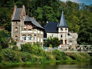 an old house on the side of a river with a bridge at Hotel Bodeblick in Treseburg