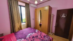 a bedroom with pink walls and a bed with purple sheets at Apartment Capt Seferovic 2 in Donji Morinj