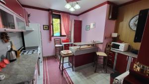 a kitchen with pink walls and bar stools at Apartment Capt Seferovic 2 in Donji Morinj