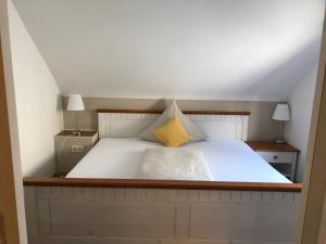 a bedroom with a white bed with a yellow pillow at Auszeit am Eifelsteig in Daun