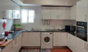 cocina con armarios blancos y lavadora en Casa Olhão Terraço: espaço, conforto e terraço com churrasqueira, en Olhão