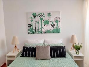 Un dormitorio con una cama con una pintura encima. en Casa Olhão Terraço: espaço, conforto e terraço com churrasqueira, en Olhão