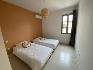 2 łóżka w małym pokoju z oknem w obiekcie Maison Diderot w mieście Aigues-Mortes