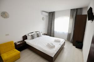 - une chambre avec un lit et une chaise jaune dans l'établissement Vila Medusa, à Vama Veche