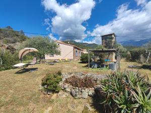 un jardin avec une maison en arrière-plan dans l'établissement Au pont de Tuarelli, Ludique, Galeria, Corse, à Manso