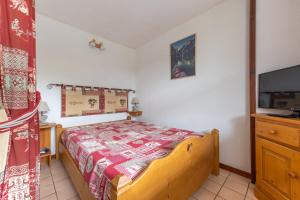 um pequeno quarto com uma cama e uma televisão em Cosy Criou - Appartement avec vue sur la montagne em Samoëns