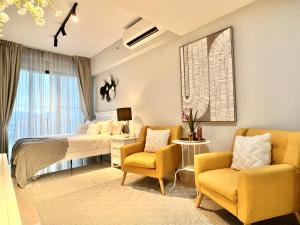 Habitación de hotel con 1 cama y 2 sillas en the Luxe by infinitum suites, en Kuala Lumpur
