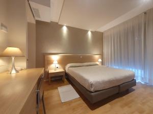 a bedroom with a bed and a desk with two lamps at Hotel Eurovil Garni in Lignano Sabbiadoro