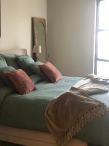uma cama verde com almofadas cor-de-rosa num quarto em NeNe em Dilbeek