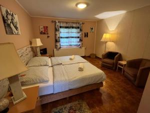a bedroom with two beds and a chair and a window at Erdei Vendégház in Bögöt