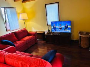 ein Wohnzimmer mit roten Möbeln und einem Flachbildfernseher in der Unterkunft Alex Chalet in Cavia
