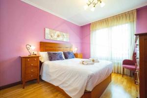 Schlafzimmer mit lila Wänden, einem Bett und einem Fenster in der Unterkunft El Rocio Apartamento in Gijón