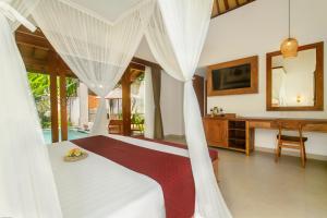 a bedroom with a bed and a desk with a mirror at de Metra Villa Ubud by Pramana Villas in Ubud