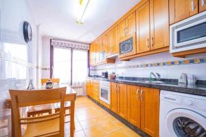 eine Küche mit Holzschränken, einer Waschmaschine und einem Trockner in der Unterkunft El Rocio Apartamento in Gijón