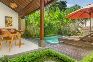 un patio con mesa, sombrilla y piscina en de Metra Villa Ubud by Pramana Villas, en Ubud