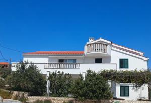 a white house with a balcony and trees at Apartman Lucy in Slatine