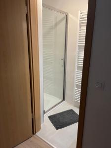 Una puerta de cristal que da a un baño con ducha. en Côté Source " Appartement " en Francorchamps