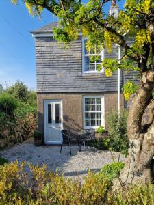 a house with two chairs and a table in front of it at Olive Cottage Small bolt hole close to Carbis Bay Beach & St Ives in Carbis Bay