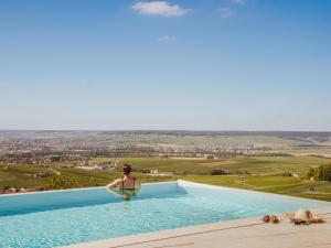 a woman sitting in a swimming pool with a view at Royal Champagne Hotel & Spa in Champillon