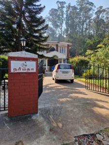 un coche blanco está estacionado frente a una casa en Narmada Holiday Home, en Ooty
