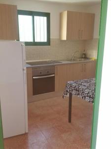 a kitchen with a table and a sink and a refrigerator at Juncalillo Garden in Las Palmas de Gran Canaria
