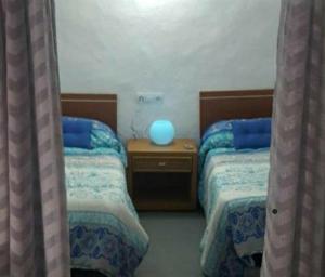 a bedroom with two beds and a blue lamp on a table at Juncalillo Garden in Las Palmas de Gran Canaria