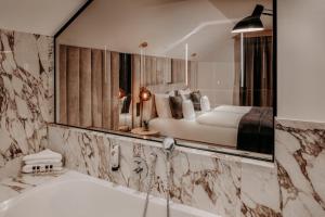 ein Bad mit einem Bett, einer Badewanne und einem Spiegel in der Unterkunft Der Eisvogel - Wellness- & Genusshotel in Bad Gögging