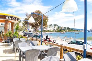 a patio with tables and chairs and a view of the water at Akkan Beach Hotel in Bodrum City