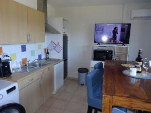 Il comprend une cuisine équipée d'un évier, d'une table et d'une télévision. dans l'établissement T2 Alba Rossa n 141 Confort, Panorama Mer Incroyable, à Serra-di-Ferro