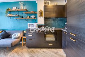 una cocina con paredes azules y un sofá en una habitación en Derbi II Apartamento muy acogedor con piscina comunitaria a pocos minutos de la playa y Port d'Aro, en Platja d'Aro
