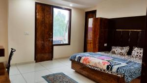 a bedroom with a bed with a wooden headboard and a window at THE RAJMANI MOTEL -- LUXURY STUDIO ROOMS -- LPU Law Gate in Phagwāra